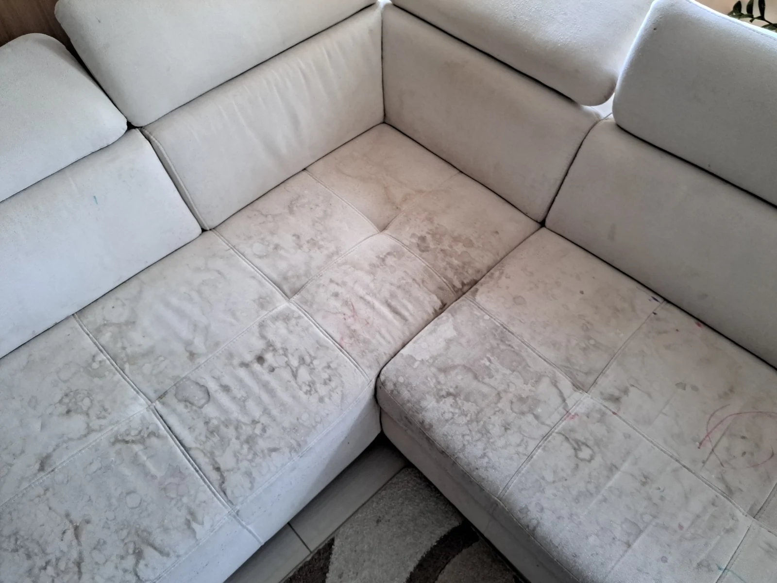 Light grey corner sofa before cleaning, with visible marks across the seat cushions